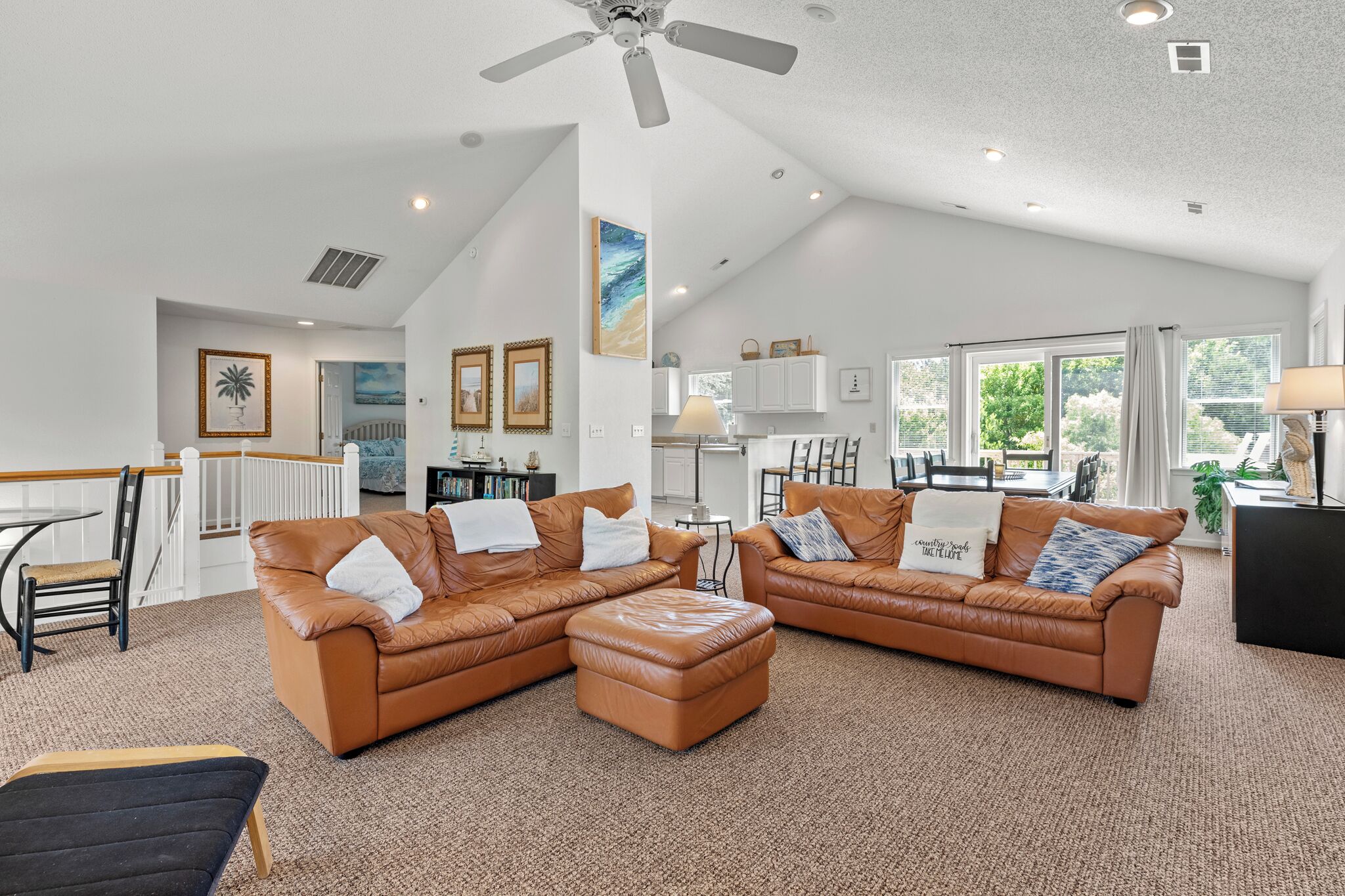 A spacious living room with a large brown leather sectional sofa, a matching ottoman, and a dining area with a table and chairs.