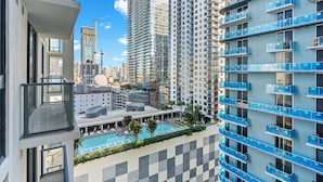 A high-rise hotel with multiple balconies, a swimming pool, and a construction crane in the background. - 11 Ne Worldcenter Experience - We Host (Miami)