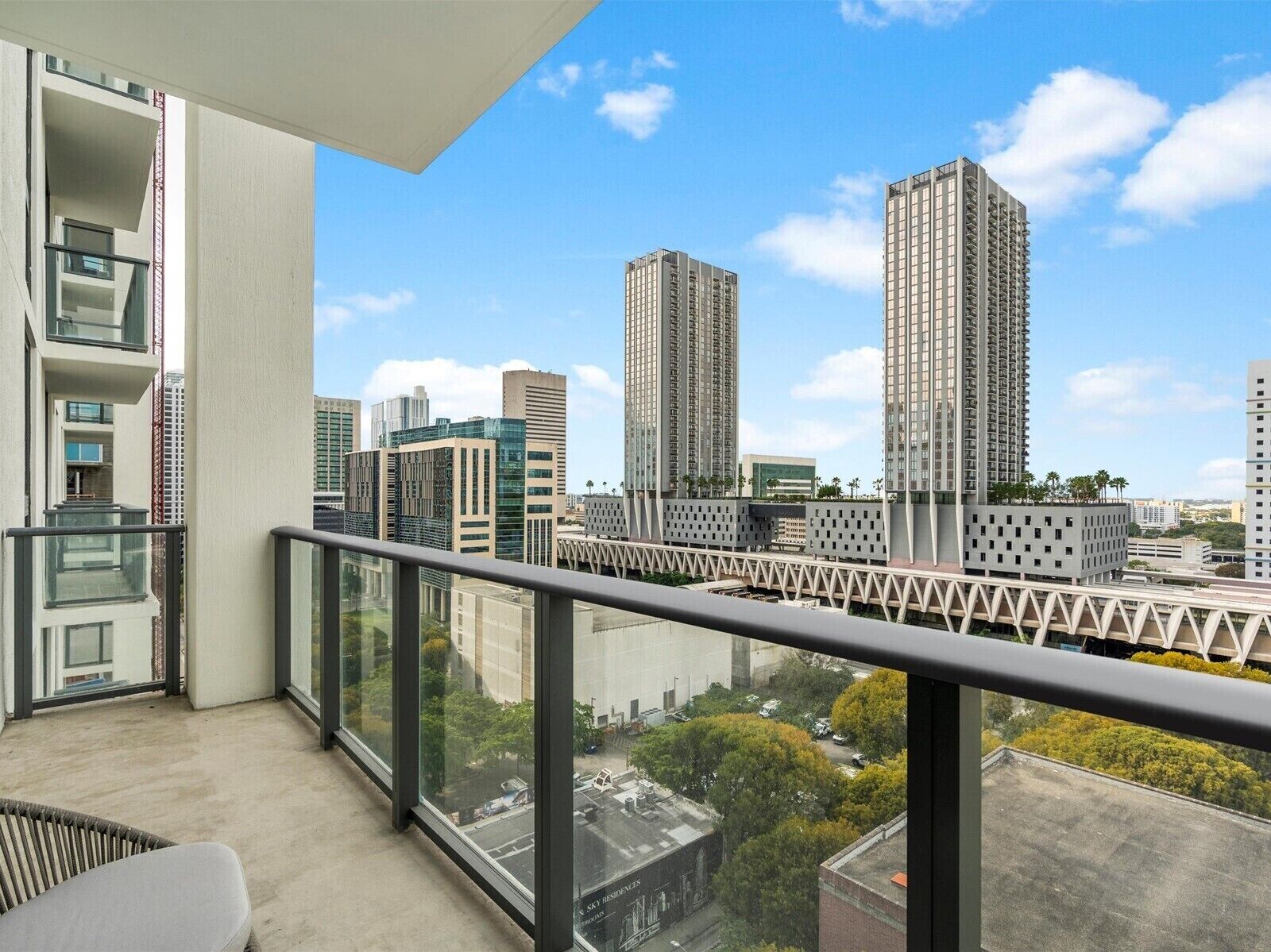 Ein Hochhaus mit modernem Design, das große Fenster und einen Balkon mit Metallgeländer aufweist.