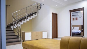 Una habitación de hotel moderna con una escalera, cama, sofá y armario.