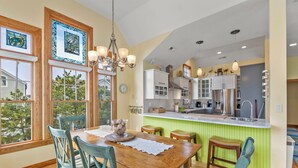 A modern kitchen with a central island, wooden dining table, and chairs. - Ocean Jewel: Private Pool | Elevator | Rec Room (Corolla)