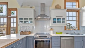 A modern kitchen with a built-in oven, dishwasher, and white cabinets. - Ocean Jewel: Private Pool | Elevator | Rec Room (Corolla)
