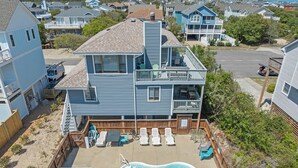 A two-story house with a backyard featuring a swimming pool, a hot tub, and a fenced patio area with lounge chairs. - Sunshine and Whiskey: Pets Allowed | Private Pool | Private Hot Tub (Corolla)