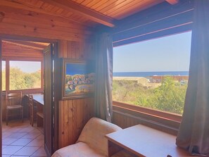 A wooden interior with a large window, a framed painting, and a seating area. - Posidonie by Interhome (L'Ile Rousse)