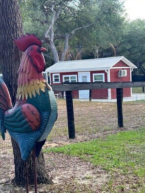 Una gran escultura de gallo junto a un edificio rojo con techo de metal.