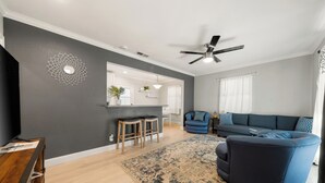 A modern living room with a dark gray accent wall, a blue sofa, a wooden coffee table, and a patterned rug.