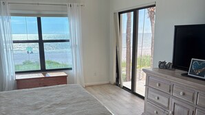 A bedroom with a bed, a dresser, a TV, and a view of the ocean. - Beachfront 2BR/2Bath Condo on the Gulf, Indian Rocks Beach, Florida (Indian Rocks Beach)