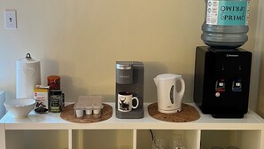 Un espacio tipo cocina con cafetera, dispensador de agua y un cartel de 'Welcome'.
