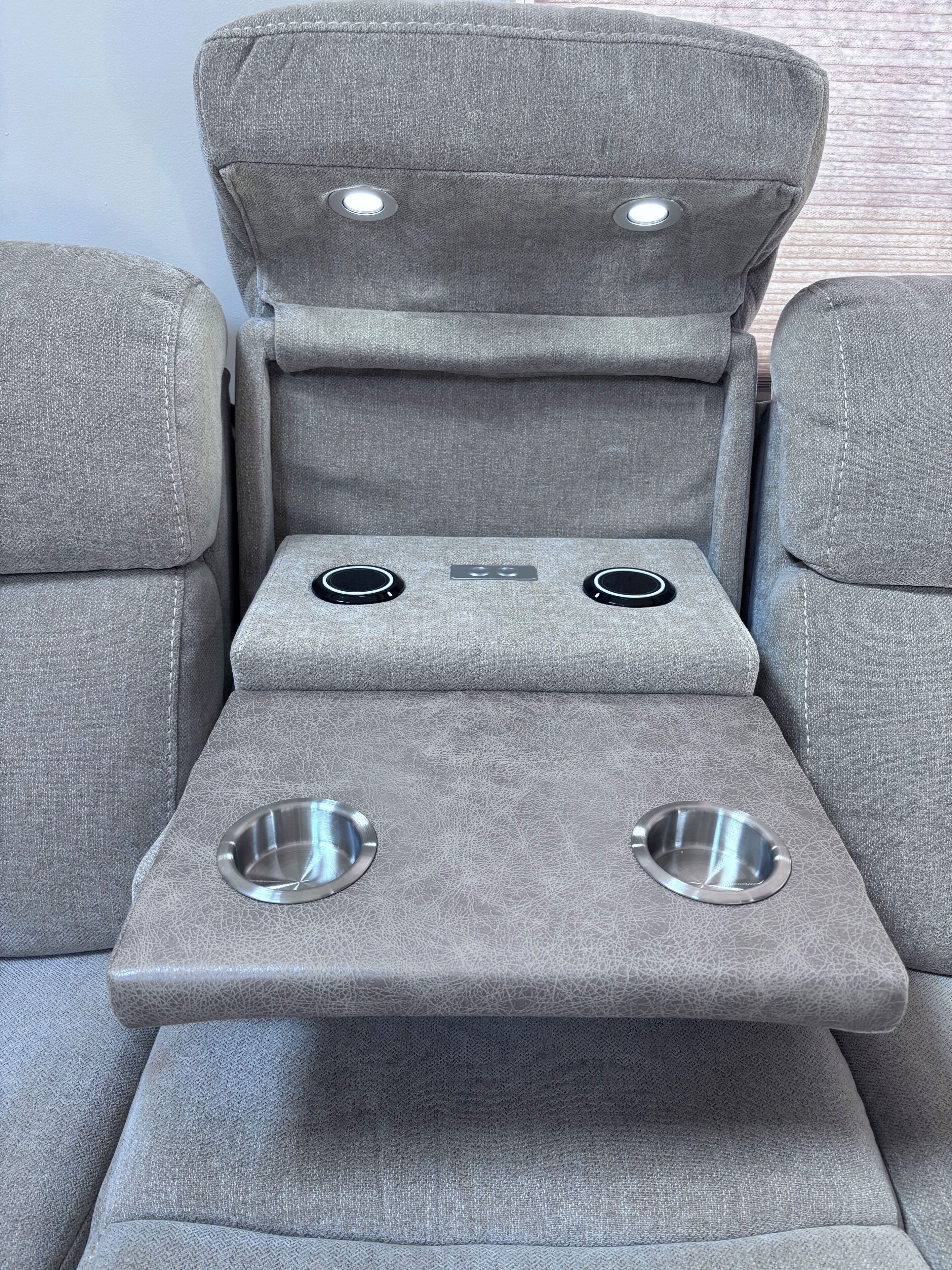 A gray massage chair with two cup holders and a control panel.