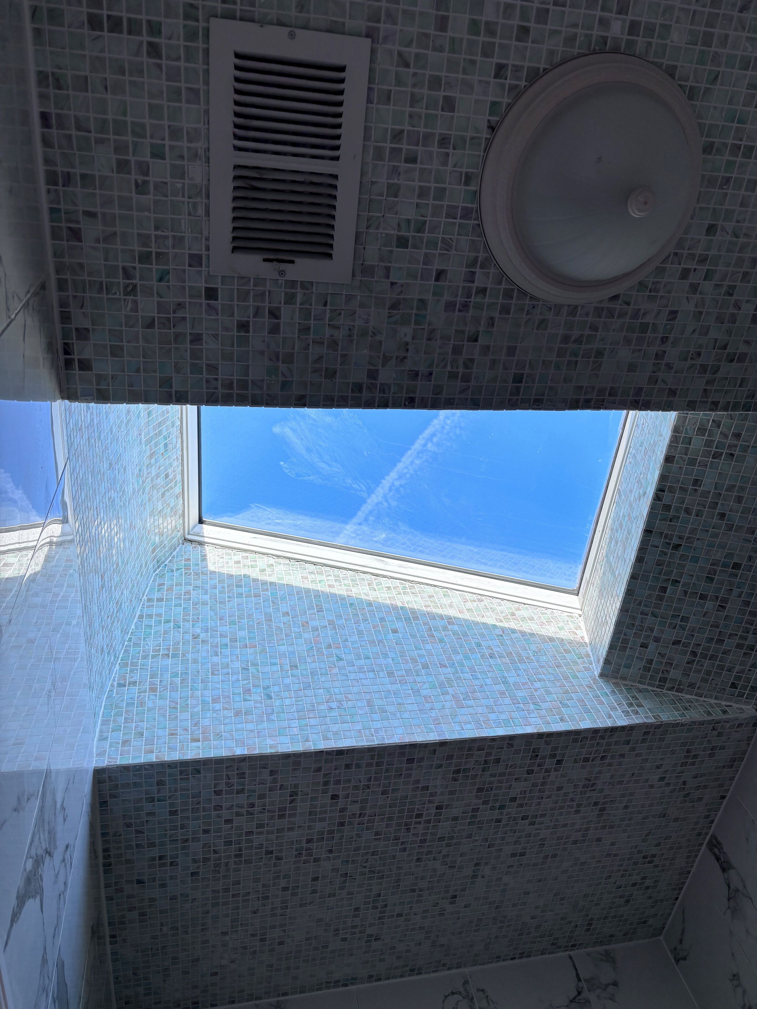Een kamer met dakraam, ventilatie en een betegelde plafond.