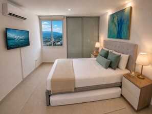Een moderne slaapkamer met een bed, nachtkastjes, een televisie, een schilderij en uitzicht op de stad.