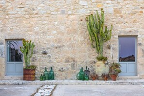 A stone building with a cactus and potted plants on the facade. - Charming Country Villa with panoramic pool (Ragusa)