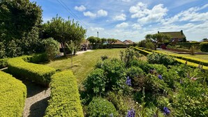 A well-maintained garden with neatly trimmed hedges and a variety of plants. - Bay View House is one of Yorkshire's premier coastal retreats. Featuring hot tub, fire pit and 4 stu (Bridlington)