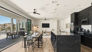 A modern kitchen with a large island, built-in appliances, and a dining area with a view.