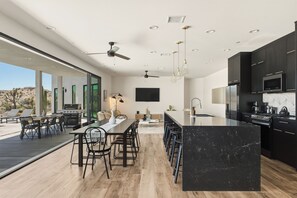 A modern kitchen with a large island, built-in appliances, and a dining area with a view.