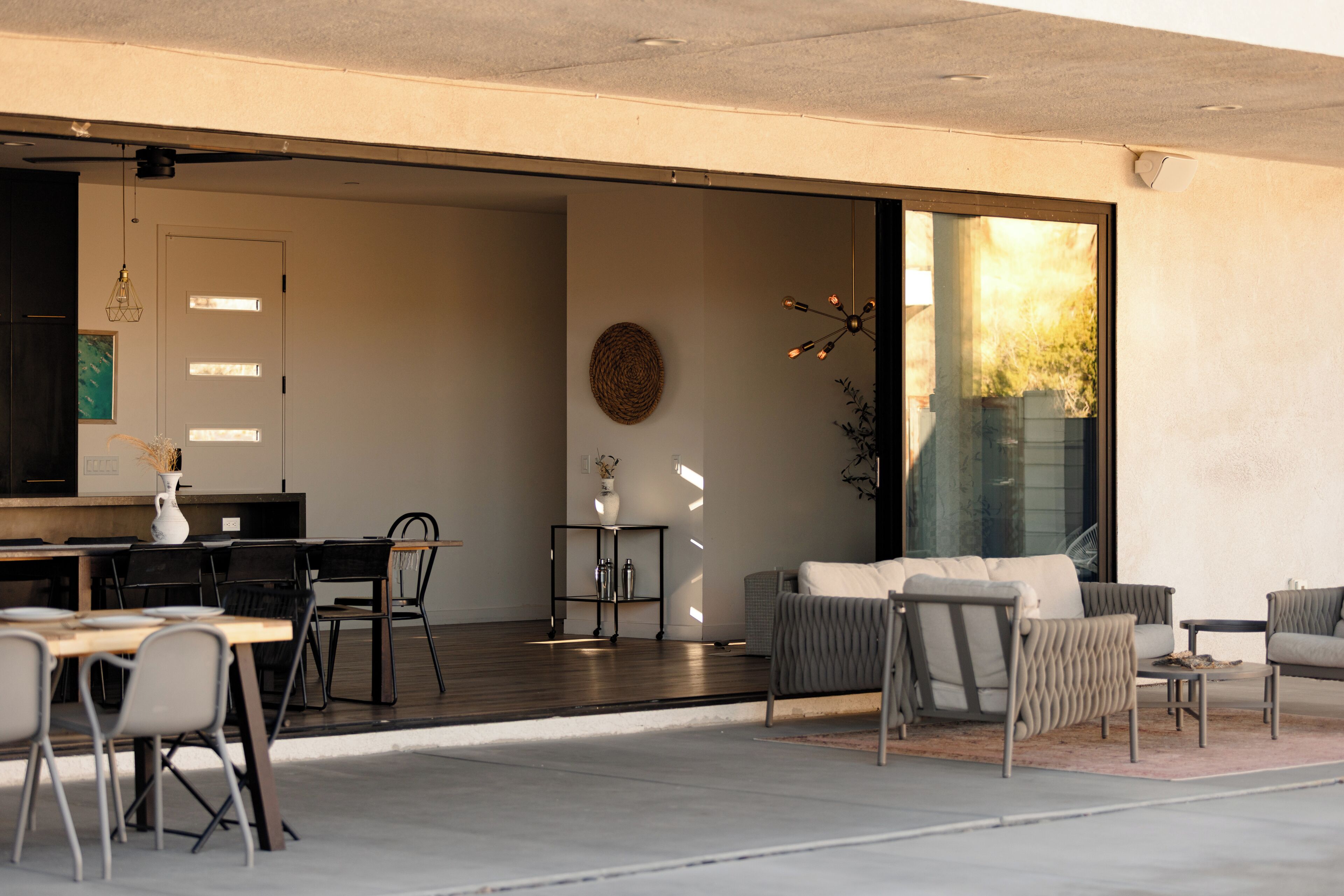 Un intérieur moderne comprenant un coin repas, un espace salon avec un canapé et des fauteuils, ainsi qu’une grande fenêtre offrant une vue dégagée.