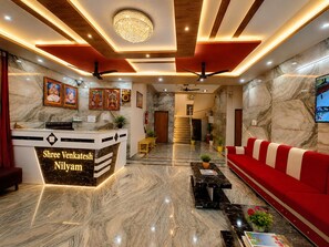 A hotel lobby with a reception desk, a red sofa, marble flooring, and a chandelier. - Shree Venkatesh Niliyam 300 M Ram Temple (Ayodhya)