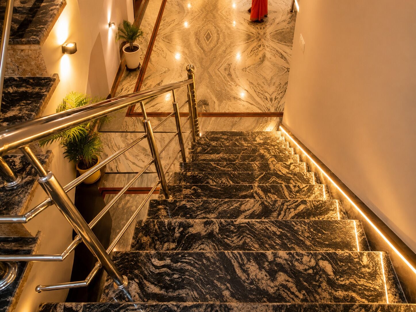 A marble staircase with a handrail, potted plants, and a red garment on the stairs.