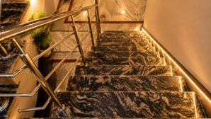 A marble staircase with a handrail, potted plants, and a red garment on the stairs. - Shree Venkatesh Niliyam 300 M Ram Temple (Ayodhya)