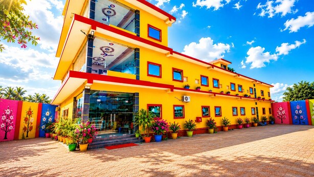 Un edificio de varios pisos con fachada amarilla, ventanas grandes y techo rojo.