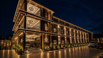 A multi-story hotel with a modern design, featuring a prominent entrance with glass doors and a well-lit facade.