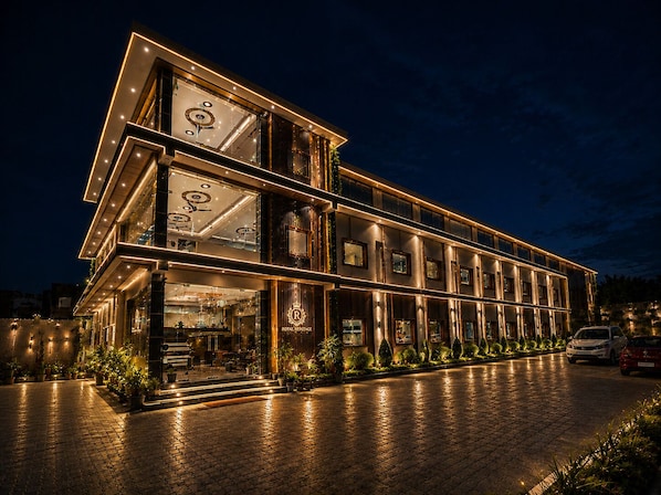 A multi-story hotel with a modern design, featuring a prominent entrance with glass doors and a well-lit facade.