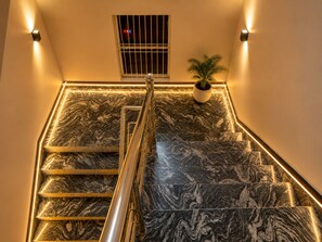 A staircase with a handrail, marble steps, and a potted plant. - Shree Venkatesh Niliyam 300 M Ram Temple (Ayodhya)