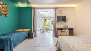 Habitació amb dos llits, un escriptori amb cadira, televisió i un balcó amb taula i cadires.
