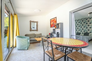 Ein Wohnzimmer mit einer Couch, einem Esstisch mit Stühlen, einem Spiegel und einem Bild an der Wand.