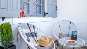 A room with a window, a chair, a small table, and a potted plant. - Sea & Sun Luxury Beach House – Elegant Cycladic Studio by Agia Paraskevi Beach (Kamari)