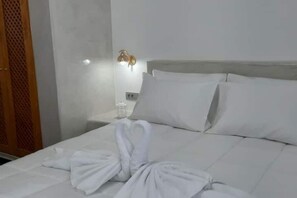Une chambre d’hôtel avec un lit bien fait, une table de chevet avec une lampe et une porte en bois.
