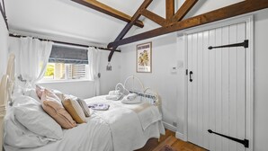 Een slaapkamer met een bed, witte gordijnen, een raam met zonwering, een radiator, een deur en een poster aan de muur.