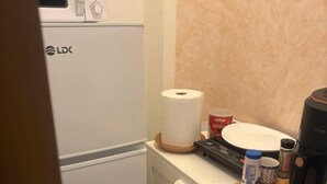 A compact kitchenette with a microwave, a coffee maker, and a small countertop with a roll of paper towels and a container of coffee creamer. - Charming Studio  Bucharest City Center! (București)