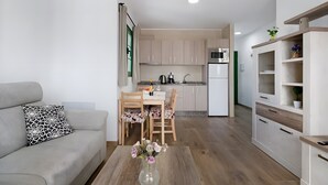 Una cocina moderna con armarios de madera, un comedor con mesa y sillas, y una sala de estar con sofá y mesa de centro.