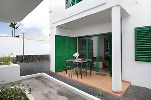 Edifício moderno com área de pátio com mesa e cadeiras, uma parede de pedra e uma porta verde.