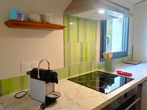 A kitchen with a built-in stove, a coffee machine, and a window with a view. - Renovated apartment within walking distance of the lively village of Flayosc (Flayosc)
