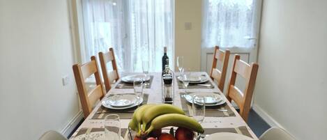 A dining table set with plates, glasses, and a fruit bowl.
