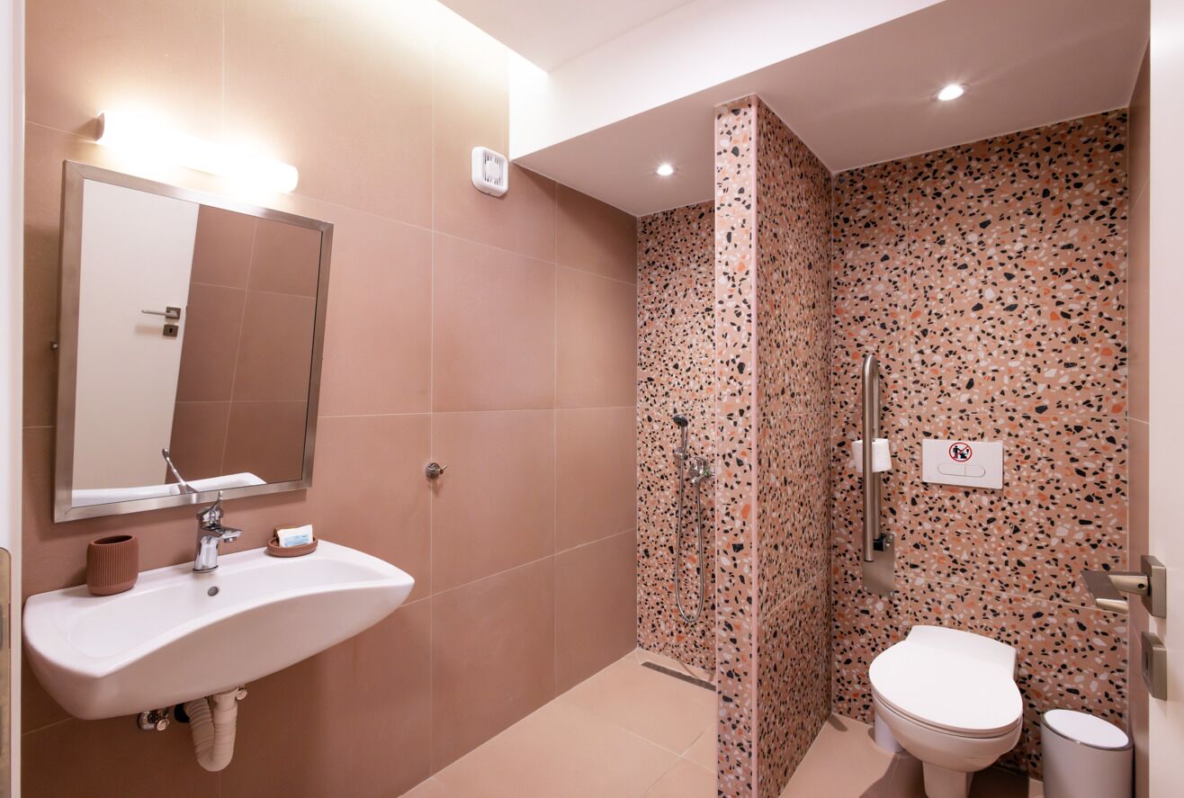 A bathroom with a sink, mirror, toilet, and shower.