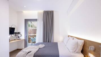 A modern hotel room with a bed, bedside table, TV, and a view of the outside.