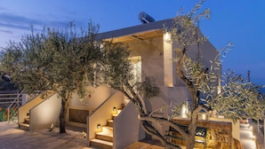 Un bâtiment moderne doté d’un escalier, d’un éclairage extérieur et d’un arbre.