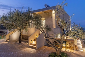 Un bâtiment moderne doté d’un escalier, d’un éclairage extérieur et d’un arbre.