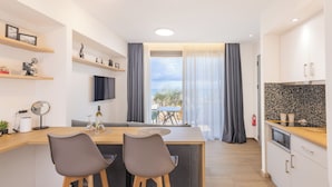 Une cuisine moderne avec un coin repas, des tabourets de bar en bois et une vue sur l’extérieur.