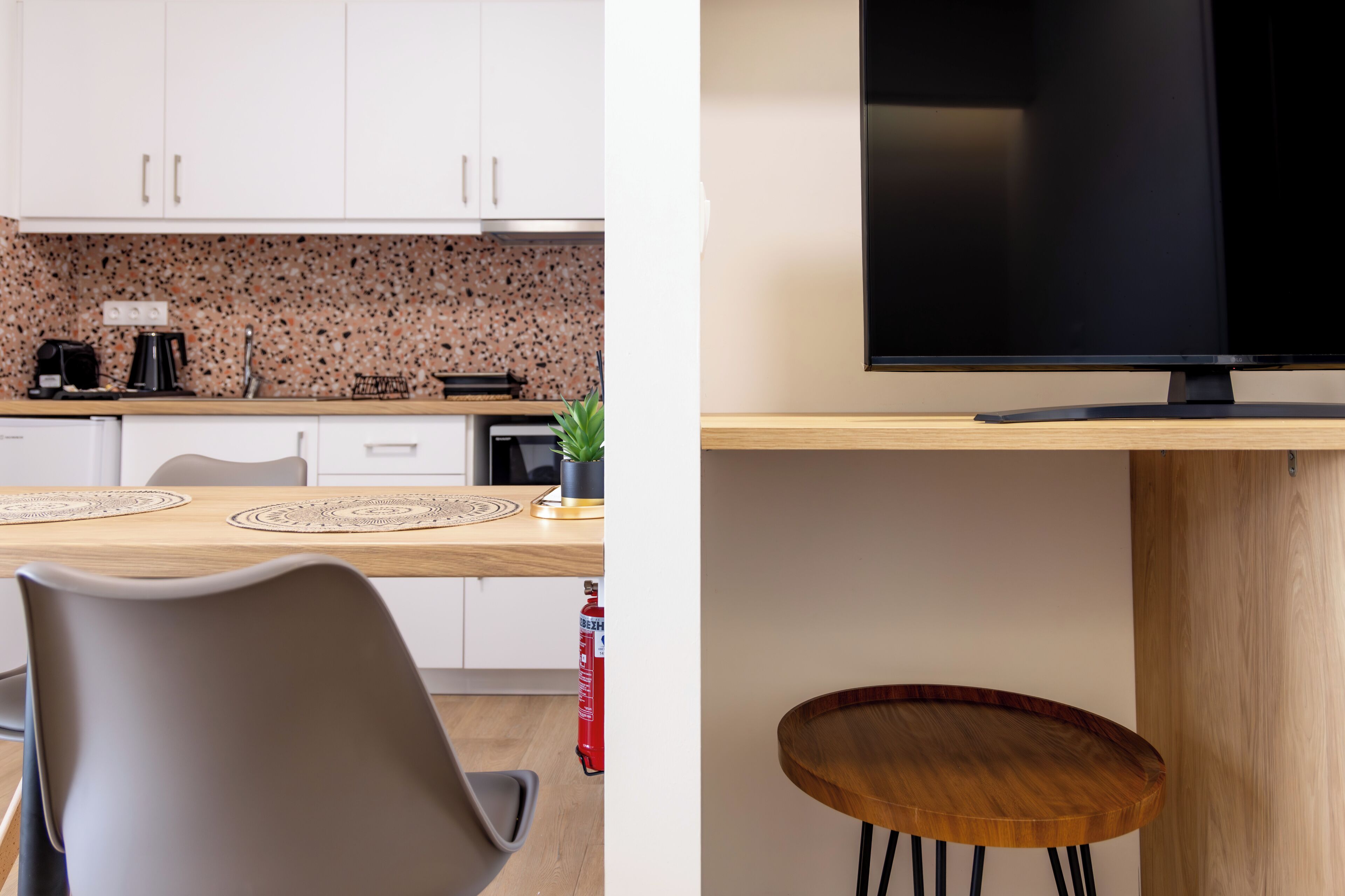 A modern kitchen with white cabinets, a granite backsplash, and a dining area with a wooden table and chairs.