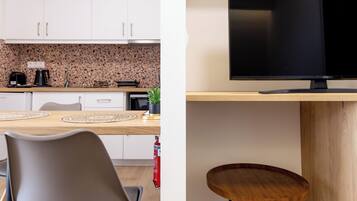 A modern kitchen with white cabinets, a granite backsplash, and a dining area with a wooden table and chairs.