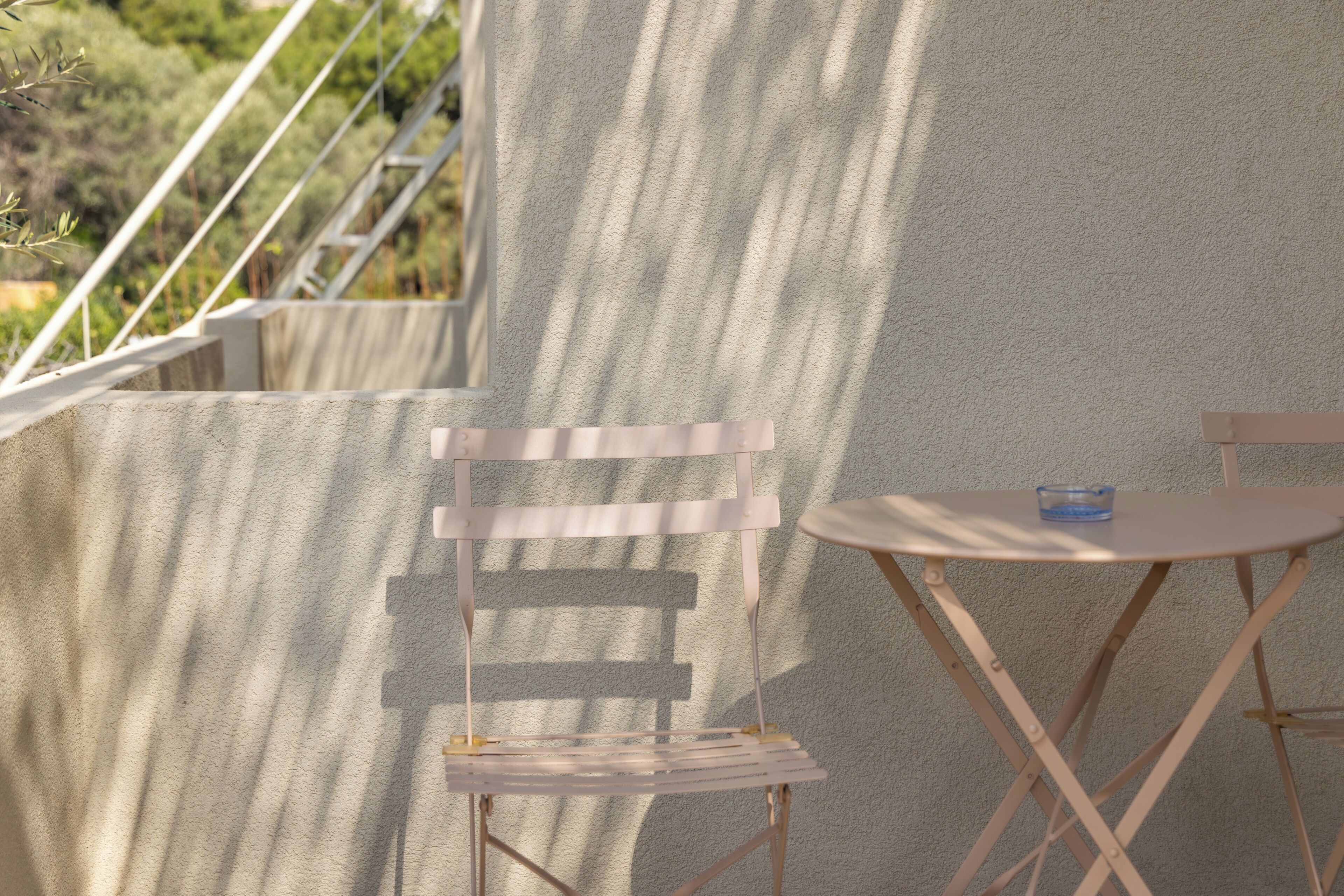 A balcony with a white chair and a small round table, both with metal frames.