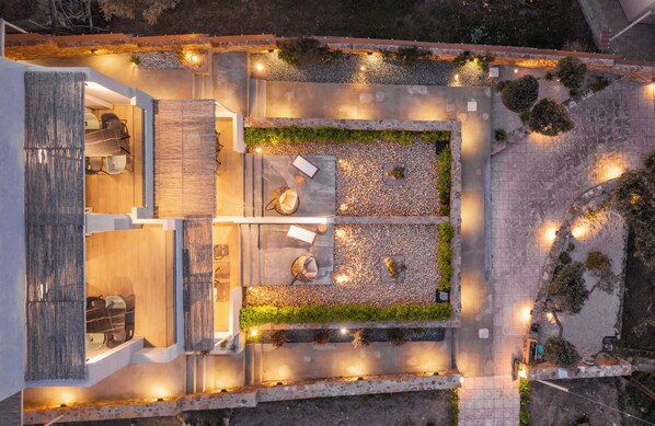 An aerial view of a modern outdoor patio area with seating, a fire pit, and decorative lighting.