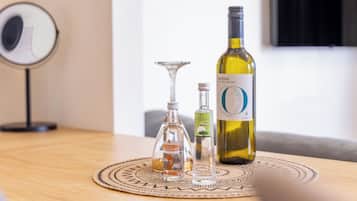 Ein Tisch mit einer Weinflasche, Olivenöl und einem Glas auf einer gewebten Tischmatte.
