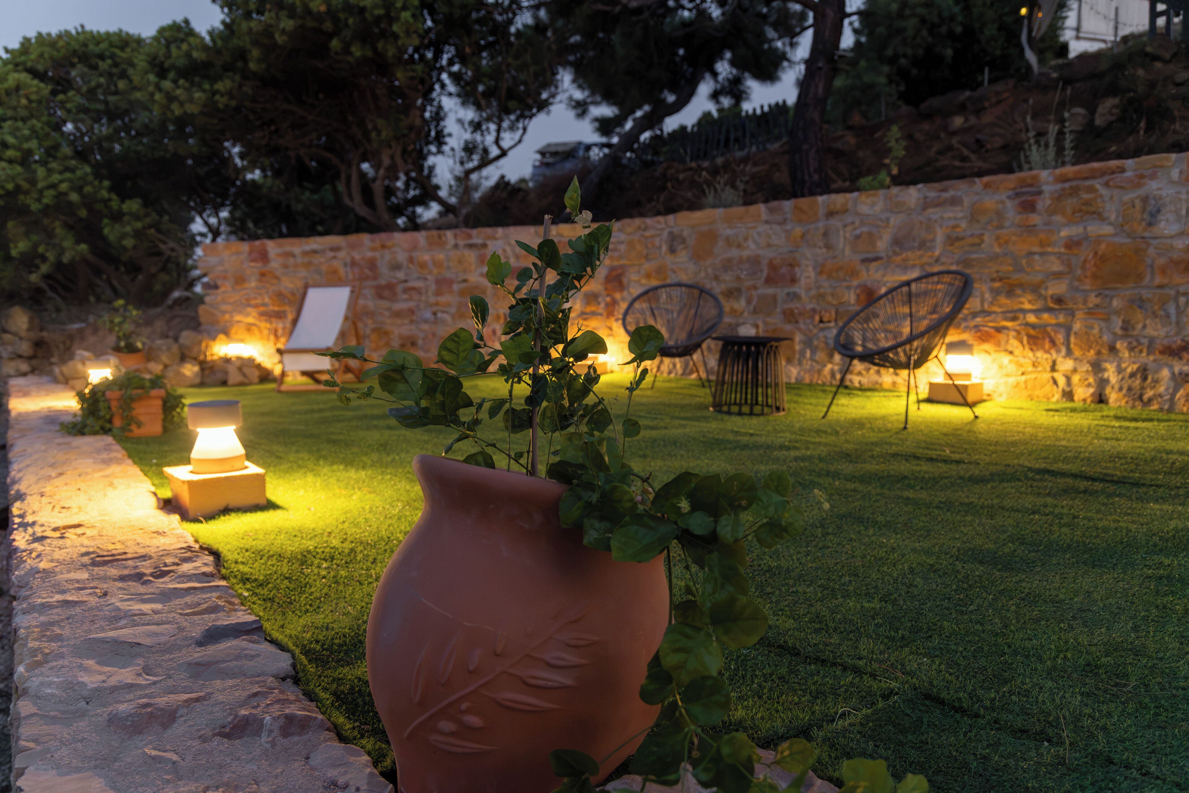 A garden area with a stone wall, a potted plant, and outdoor furniture.