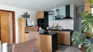 Una cocina moderna con armarios de madera, una isla central y un comedor con sillas de mimbre.