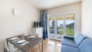 A dining area with a table set for four, a sofa, and a TV. - San Sivino 108 Lake View with Pool (Manerba del Garda)